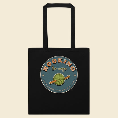 Black cotton tote bag with Hooking to Cope crochet badge artwork