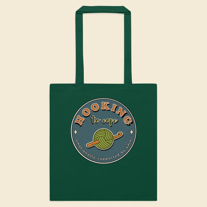 Bottle green cotton tote bag with Hooking to Cope crochet badge artwork