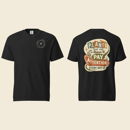 Front and back of a black heavyweight T-shirt: a small cream logo mark on the chest and Plants Give You a Reason artwork on the back