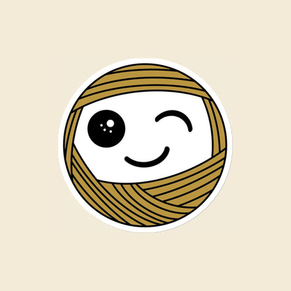 Wink, a winking mustard Yarn Creature magnet, 4 × 4 in, on a cream background